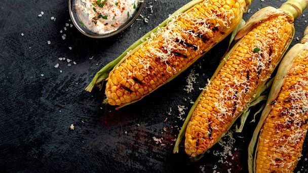 Grilled corncobs with cheese on dark background. Harvest food concept. Top view, flat lay, copy space - Foto, Bild