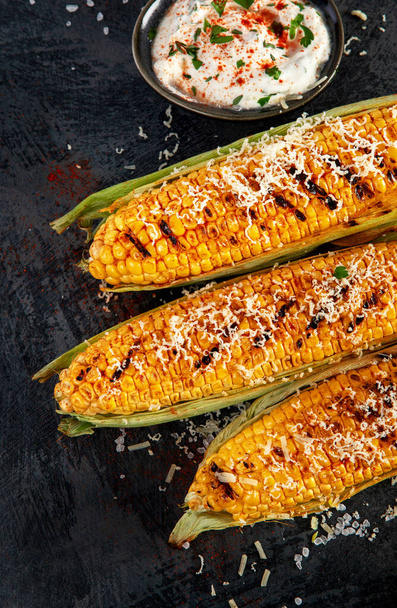 Grilled corncobs with cheese on dark background. Harvest food concept. Top view, flat lay, copy space - Φωτογραφία, εικόνα