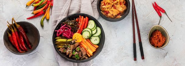 Bibimbap with snacks on gray background. Traditional Korean food. Top view, flat lay, copy space, panorama - Foto, immagini