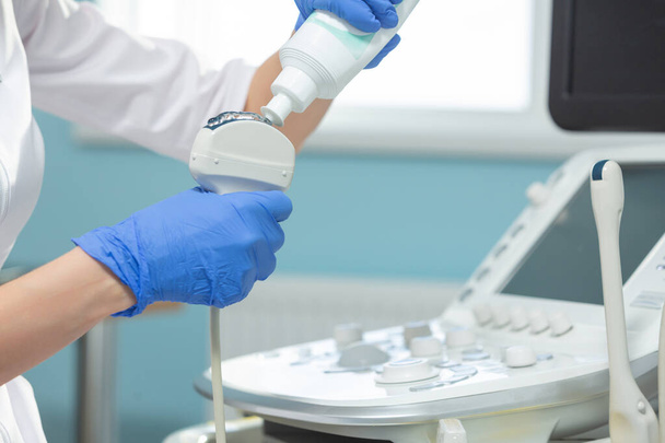 Close-up van de toepassing van medische gel op de ultrasone diagnostische sensor. De arts bereidt zich voor op de echografie. - Foto, afbeelding