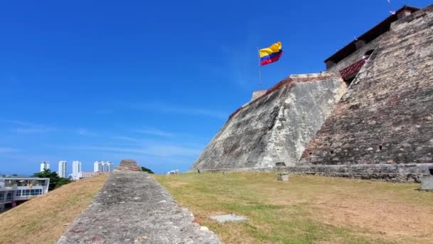 Bandera ondeando frente al Castillo de San Felipe de Barajas. Vista panorámica del horizonte moderno de Cartagena cerca del centro histórico de la ciudad y la zona hotelera del complejo - Imágenes, Vídeo