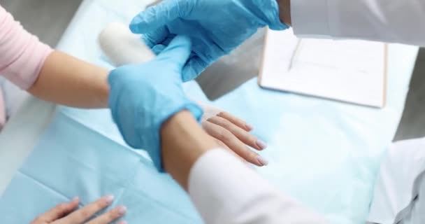 Doctor traumatoloog verbinden patiënt hand met verband in kliniek closeup 4k film - Video