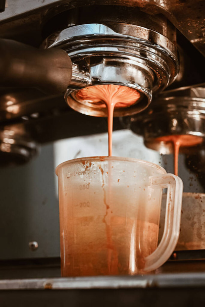 Κοντινό πλάνο της μηχανής Espresso που φτιάχνει έναν espresso με ένα "γυμνό" portafilter, κατευθύνει το ζεστό νερό υψηλής πίεσης μέσα από το δίσκο του καφέ. Η μηχανή espresso είναι ένα εργαλείο που χρησιμεύει για την παρασκευή φρέσκου καφέ. - Φωτογραφία, εικόνα
