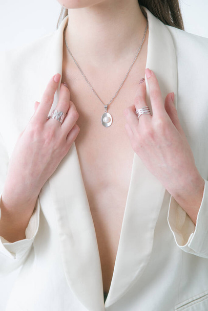 Tendance bijoux en argent sertis de perles sur une belle jeune fille dans une veste blanche à la mode. Beauté et mode  - Photo, image