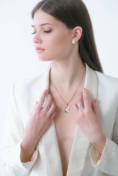 Trending silver jewelry set with pearls on a beautiful young girl in a white fashionable jacket. Beauty and fashion  - Φωτογραφία, εικόνα