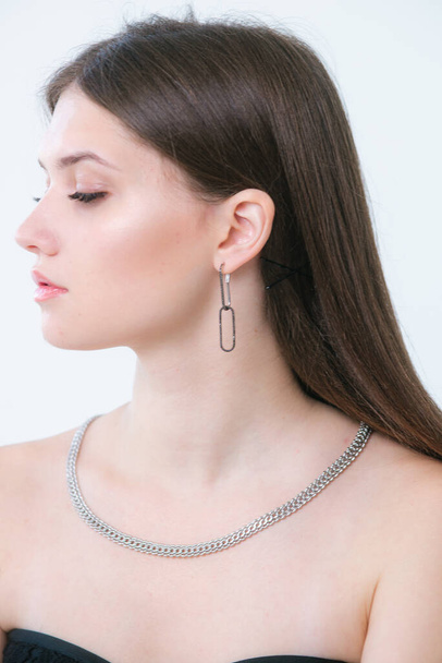 Trendy silver earrings and necklace  on a beautiful young girl with long dark hair. Beauty and fashion  - Photo, Image