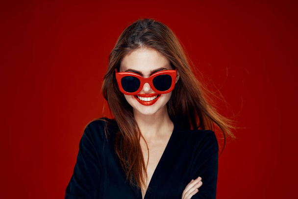 pretty woman wearing sunglasses fashion posing hairstyle red background - Fotó, kép
