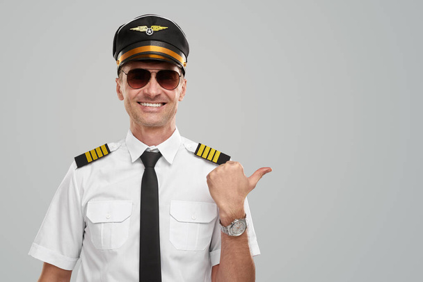 Confident male pilot smiling and pointing away - Foto, Bild