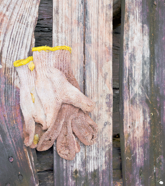 Nahaufnahme von schmutzigen Handschuhen auf Holztisch - Foto, Bild