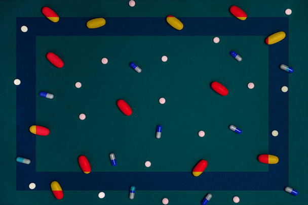 Разнообразие лекарств в капсулах и таблетках разных цветов на синем фоне - Фото, изображение
