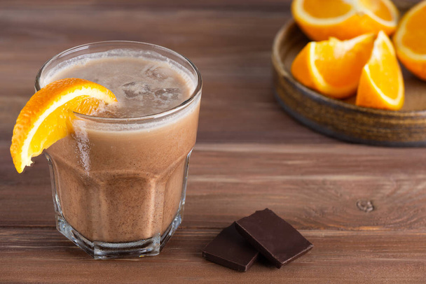 Caffè Mochaccino con cioccolato, arancia, latte di cocco e ghiaccio in un bicchiere su un tavolo di legno. - Foto, immagini