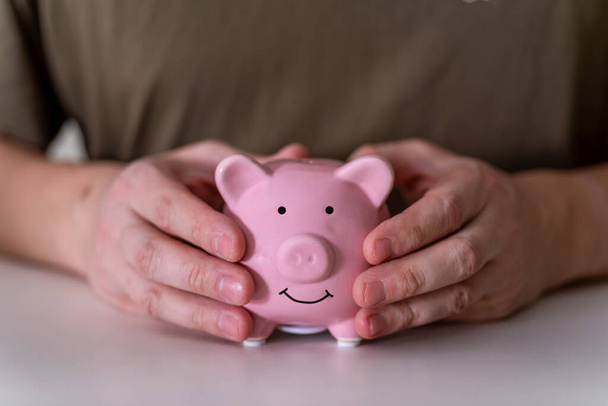The businessman's hands hold a pink piggy bank. The concept of money accumulation. - Фото, зображення