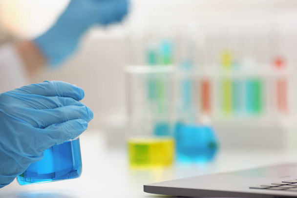 Microbiólogo mãos em luvas segurar líquido azul - Foto, Imagem
