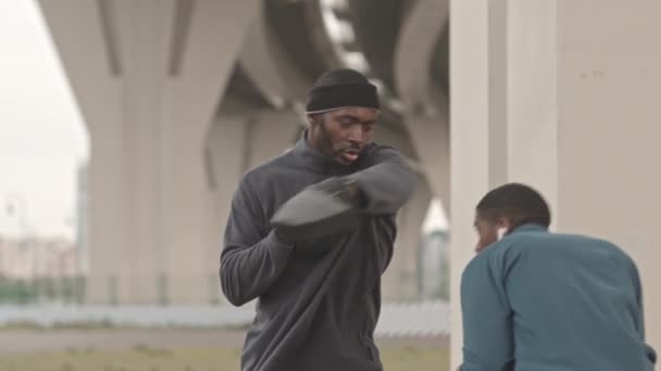 Média lentidão tiro de treinamento treinador de boxe afro-americano grave com o jovem ao ar livre na manhã fria - Filmagem, Vídeo