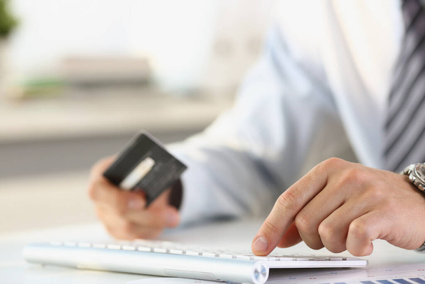 Un homme avec une carte de crédit à la main tape sur le clavier - Photo, image