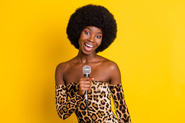 Photo of charming excited dark skin woman dressed leopard outfit smiling singing isolated yellow color background - Foto, Bild
