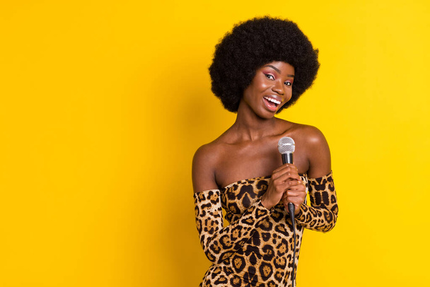Photo portrait curly woman in leopard outfit singing in microphone on stage isolated bright yellow color background copyspace - Foto, Bild