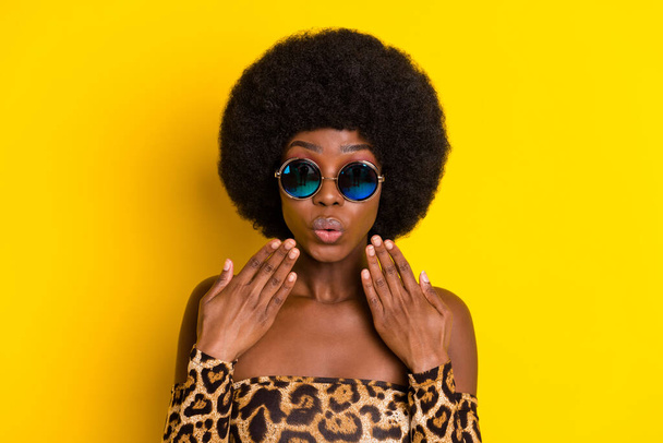 Photo of sweet impressed dark skin woman dressed leopard outfit glasses arms cheeks isolated yellow color background - Photo, image
