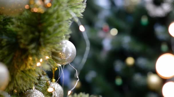 金のボールの装飾とコピースペースを背景に輝くカラフルなライトを持つ伝統的な人工クリスマスツリー。ソフトフォーカスクリスマスの装飾。季節の冬休み。新年のコンセプト. - 映像、動画