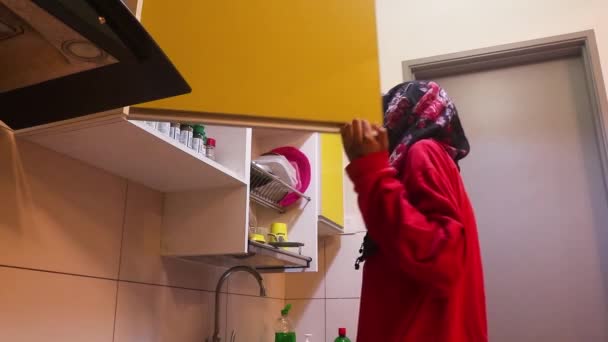  Muszlim hölgy nyitó szekrények egy konyhában - alacsony szögben. - Felvétel, videó