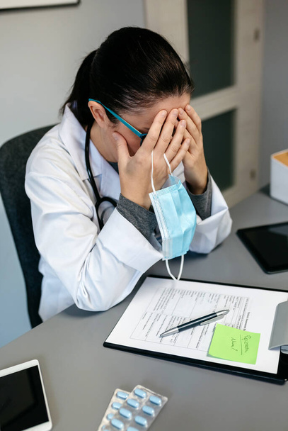 Женщина-врач с пандемической усталостью закрывает лицо - Фото, изображение