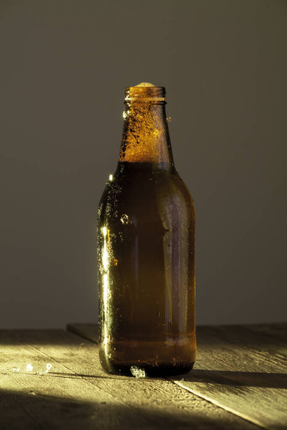 A vertical shot of a bottle of beer on a wooden surface - Foto, Imagem
