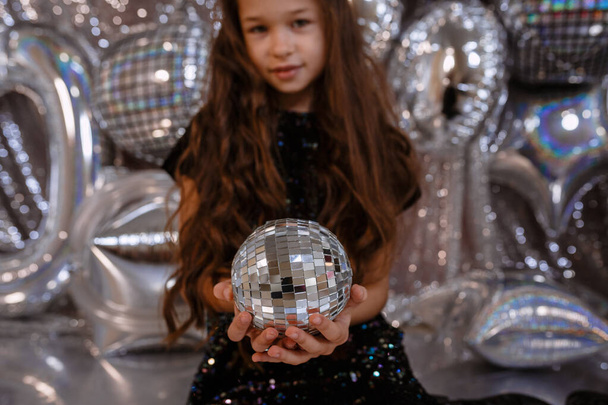 cute little child girl in black dress on on a silver shiny background. birtday party for girl - Фото, изображение