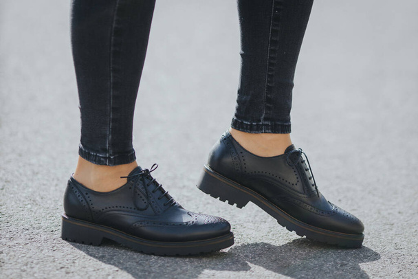The legs of a female wearing fashionable black loafers - Zdjęcie, obraz