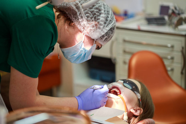 Hoito hammaslääkäri, oikomishoidon laittaa hammasraudat teini tyttö, asentamalla hammasraudat järjestelmä. - Valokuva, kuva