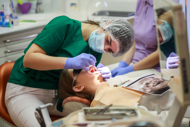 Traitement par un dentiste, un orthodontiste pose un appareil dentaire sur une adolescente, installant un système d'appareil dentaire. - Photo, image