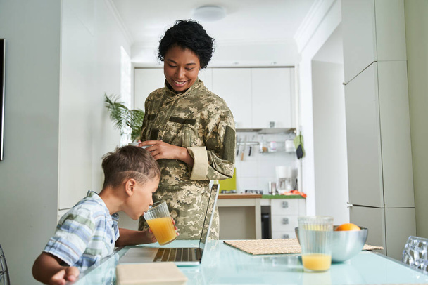 Woman in military uniform looking at her little son with love and tenderness - Foto, Imagen