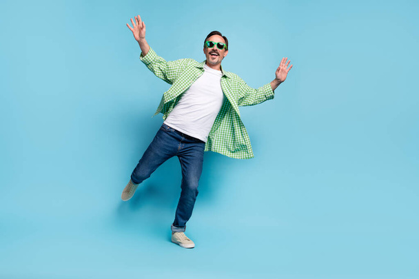 Full length body size view of attractive cheerful man dancing having fun resting isolated over vivid blue color background - Foto, imagen