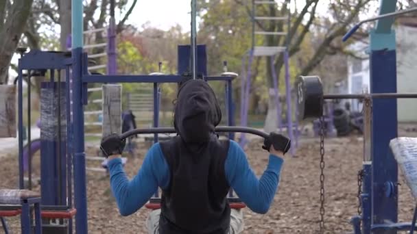 Ισχυρός Grey-Haired Man With Dreadlocks exercise Με μια εκπαιδευτική συσκευή στο Open Air Gym το φθινόπωρο. Ρίχνω ένα βάρος. City street προπόνηση - Πλάνα, βίντεο