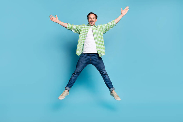 Full length body size view of attractive cheerful free man jumping having fun isolated over bright blue color background - Zdjęcie, obraz