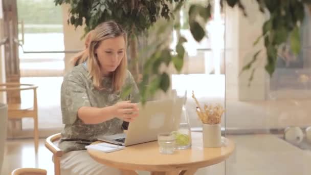 Mujer sentada en la mesa con portátil en la cafetería  - Imágenes, Vídeo