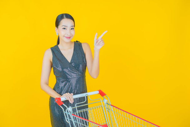 Portrait beautiful young asian woman smile with grocery basket from supermarket on color background - Фото, изображение