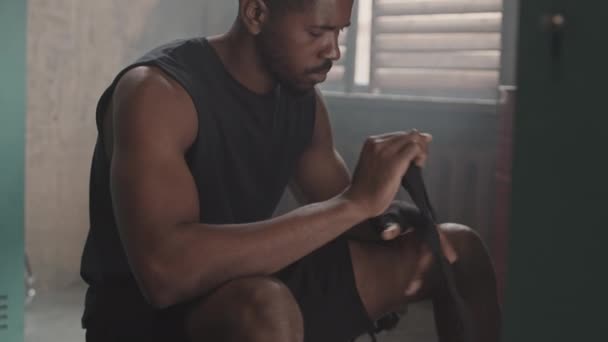 Slowmo shot di giovane muscoloso pugile afro-americano bendaggio mani con involucro nero prima di indossare guanti - Filmati, video