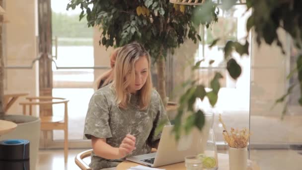 Kafede dizüstü bilgisayarlı bir kadın oturuyor.  - Video, Çekim