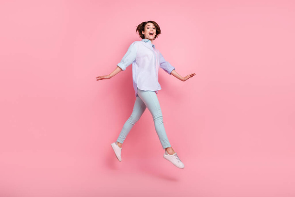 Pełna długość ciała rozmiar zdjęcie kobieta uśmiechając się skacząc wesoły odizolowany pastel różowy kolor tło - Zdjęcie, obraz