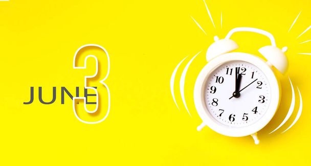 3 Ιουνίου. Ημέρα 3η του μήνα, ημερομηνία ημερολογίου. Λευκό ξυπνητήρι με ημερολογιακή ημέρα σε κίτρινο φόντο. Μινιμαλιστική αντίληψη του χρόνου, διορία, ώρα για δουλειά, πρωί. Καλοκαιρινό μήνα, ημέρα του έτους έννοια - Φωτογραφία, εικόνα