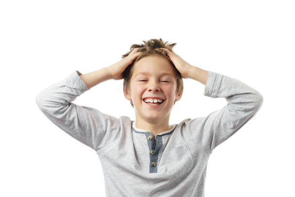 γελαστό παιδί που αγγίζει τα μαλλιά με τα χέρια, απομονωμένο σε λευκό φόντο - Φωτογραφία, εικόνα