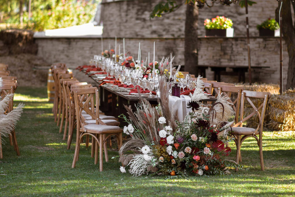 春の庭でプレートやサービットと美しい装飾が施された非常によく装飾された結婚式のテーブルの予定。結婚式の日にテーブルの上の美しい花。エレガントなディナーテーブル。ボホ結婚式. - 写真・画像
