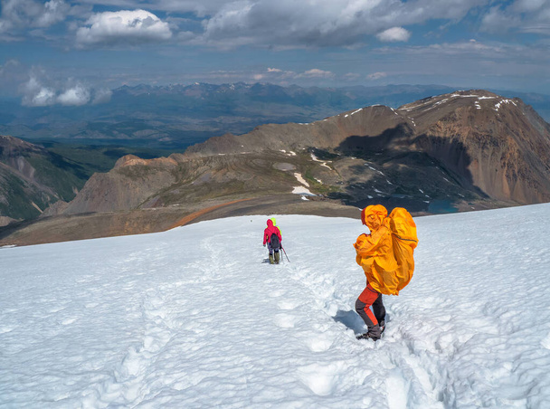 Βαριά αναρρίχηση μια ομάδα ορειβάτες σε μια απότομη χιονισμένη πλαγιά. Ομαδική εργασία και νίκη, ομαδική εργασία ανθρώπων σε δύσκολες συνθήκες. Ταξιδιωτικός τρόπος ζωής, πεζοπορία σκληρό κομμάτι, περιπέτεια έννοια στις χειμερινές διακοπές. - Φωτογραφία, εικόνα