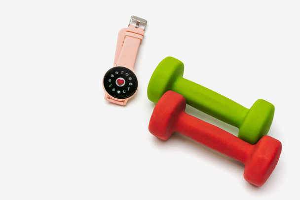 Krasnoyarsk, Russia - November, 22, 2021: Smart wrist watch and dumbbells on a white isolated background. Health control concept with smart watch in fitness class. - Foto, imagen