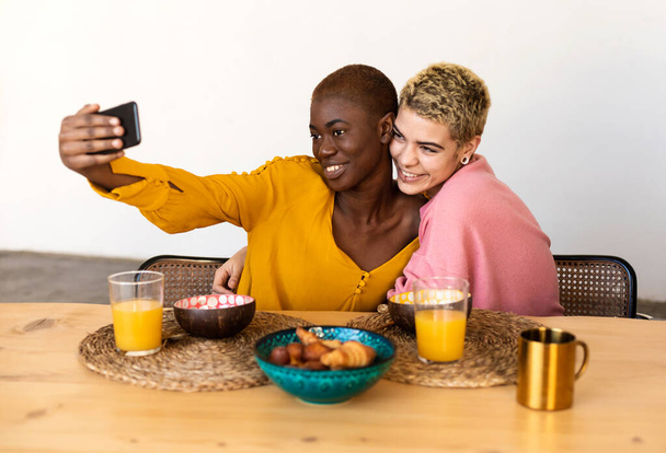 Multiethnic female friends taking a selfie while having dinner - Fotografie, Obrázek