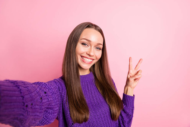 Portret van optimistisch meisje do selfie show v-teken slijtage lila trui geïsoleerd op pastel roze kleur achtergrond - Foto, afbeelding