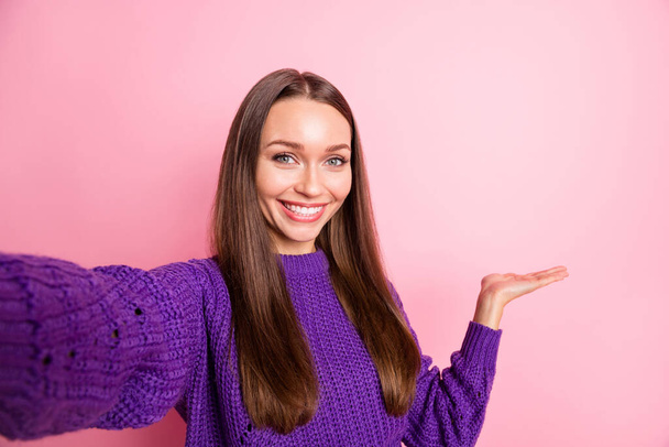 Photo of pretty positive person take selfie hand indicate empty space isolated on pink color background - Foto, afbeelding