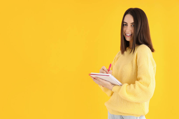 Привлекательная девушка с блокнотом на желтом фоне - Фото, изображение