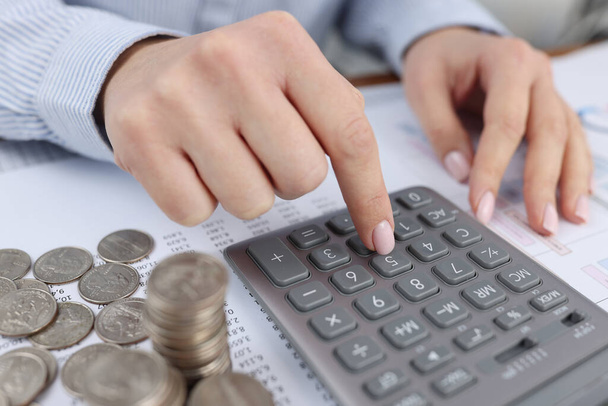 Woman counting on calculator at table with documents and coins closeup - Photo, Image