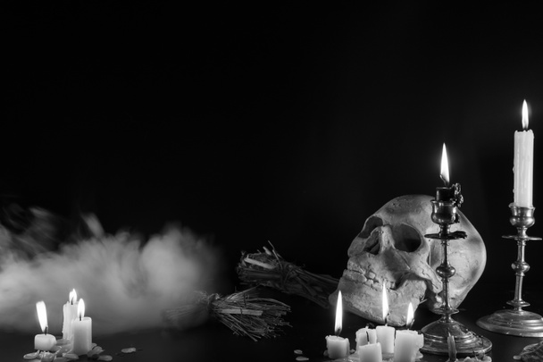 Old Skull and candle with incense on old altar plate which has dim light. Select focus, black background. Straw voodoo dolls. Copy space Mysical, terrible smoke of evil - Photo, Image